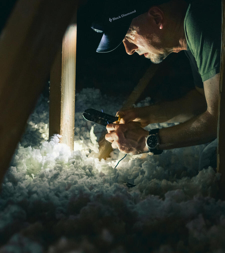 A yellow house with brown trim and a front porch. There are leaves on the ground and a cloudless blue sky.